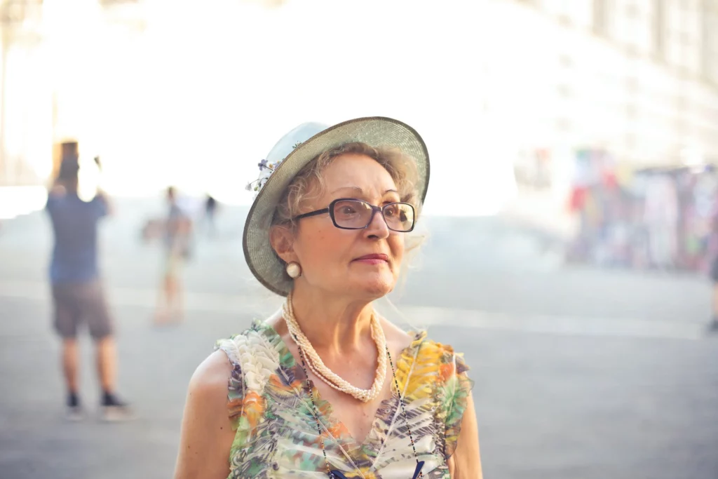 An older woman wearing glasses and a hat.