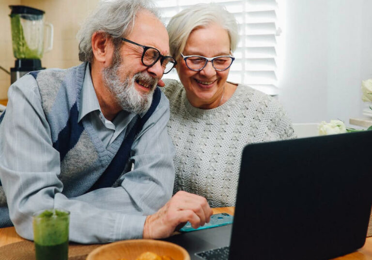 An older couple looking at a laptop.