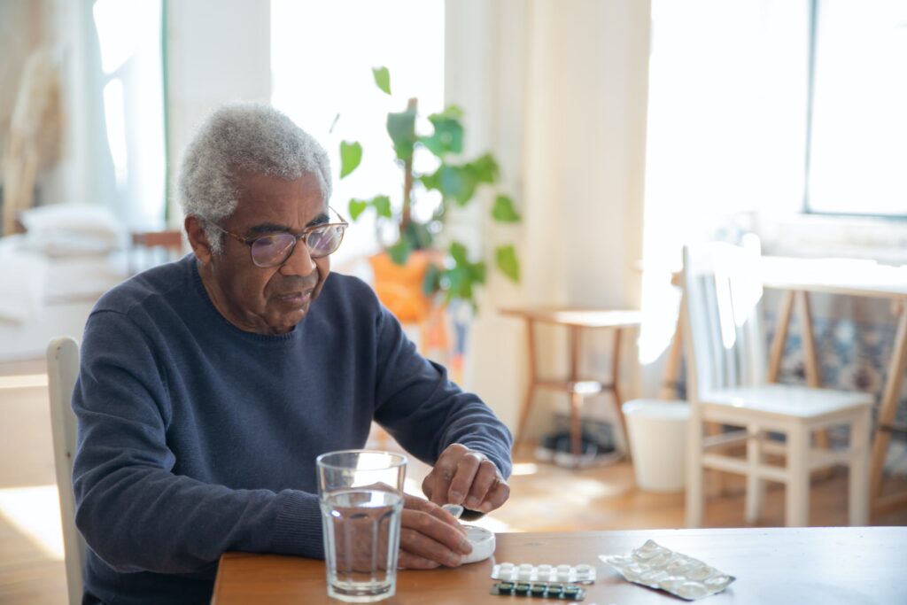 An older man is sitting at a table with a glass of water.