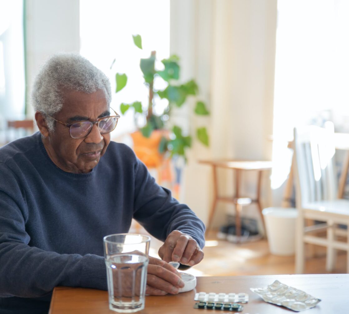 An older man is sitting at a table with a glass of water.